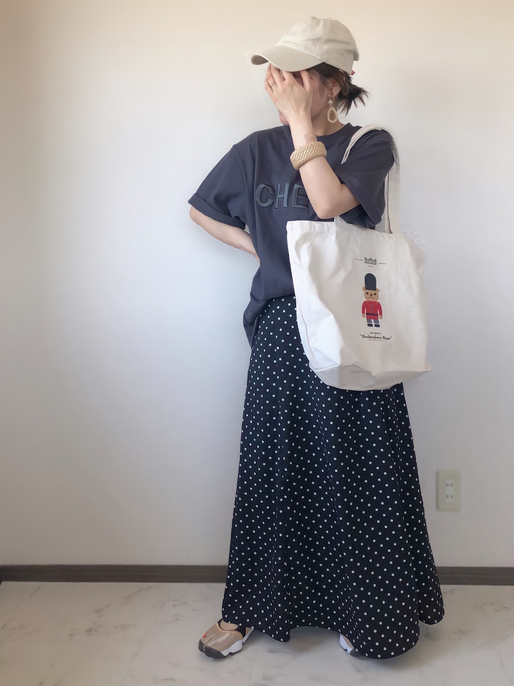 グレー系のTシャツ/カットソー、ブラック系のスカート、ベージュ系のトートバッグを着用したレディースの春コーディネートの1枚目の写真