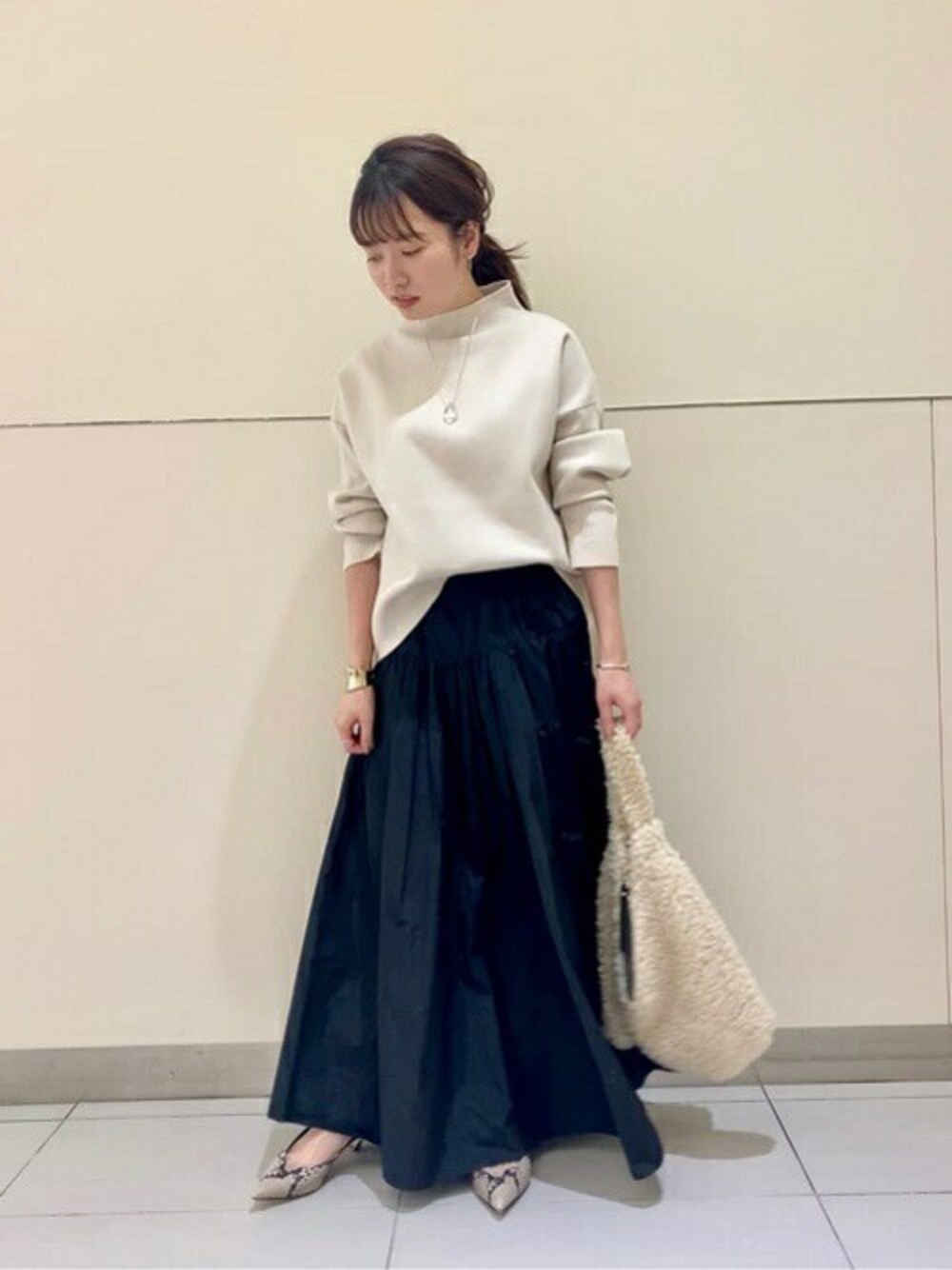 ホワイト系のニット/セーター、ブラック系のスカート、ホワイト系のトートバッグを着用したレディースの秋コーディネートの1枚目の写真