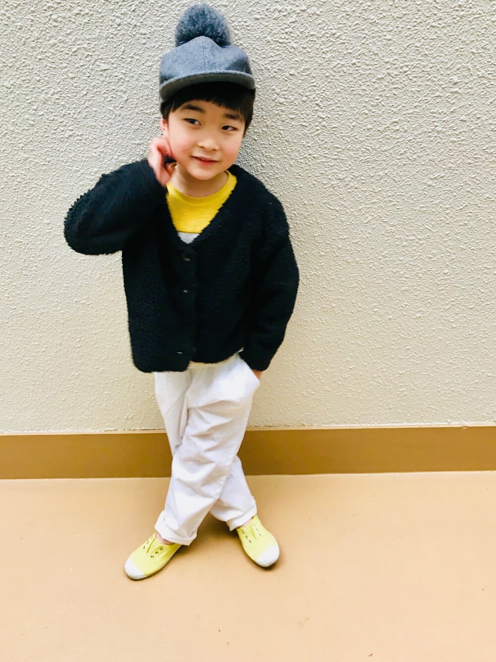 「冬コーデ、昭和感、ホワイトパンツ、ボアカーディガン、ボア、ポンポン帽子、男の子コーデ、カジュアル、イエロー、ポージング」｜「petit mainのボンボン付きキャップ（キャップ、グレー系）」を使った、うまくんのかぞくさん（キッズ・100cm）の冬コーディネートの1枚目の写真