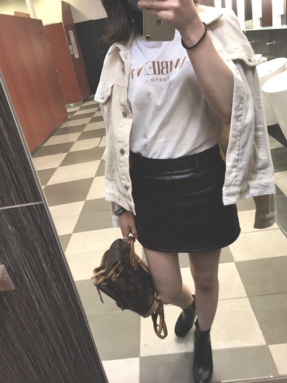 ブラウン系のスカート、ブラック系のブーツ、ホワイト系のTシャツ/カットソーを着用したレディースの秋コーディネートの1枚目の写真