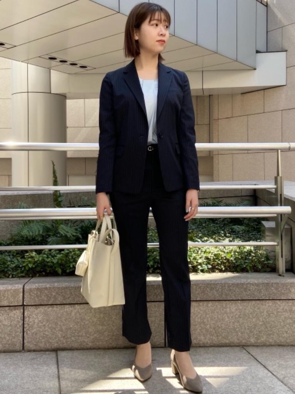 グレー系のパンプス、グレー系のショルダーバッグ、ブルー系のTシャツ/カットソーを着用したレディースの春コーディネートの1枚目の写真