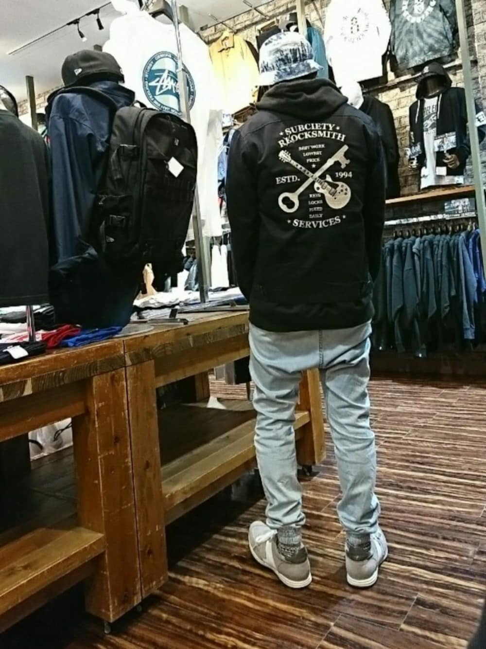 ブラック系のブルゾン、ブルー系のデニムパンツ、グレー系のスニーカーを着用したメンズの秋コーディネートの1枚目の写真