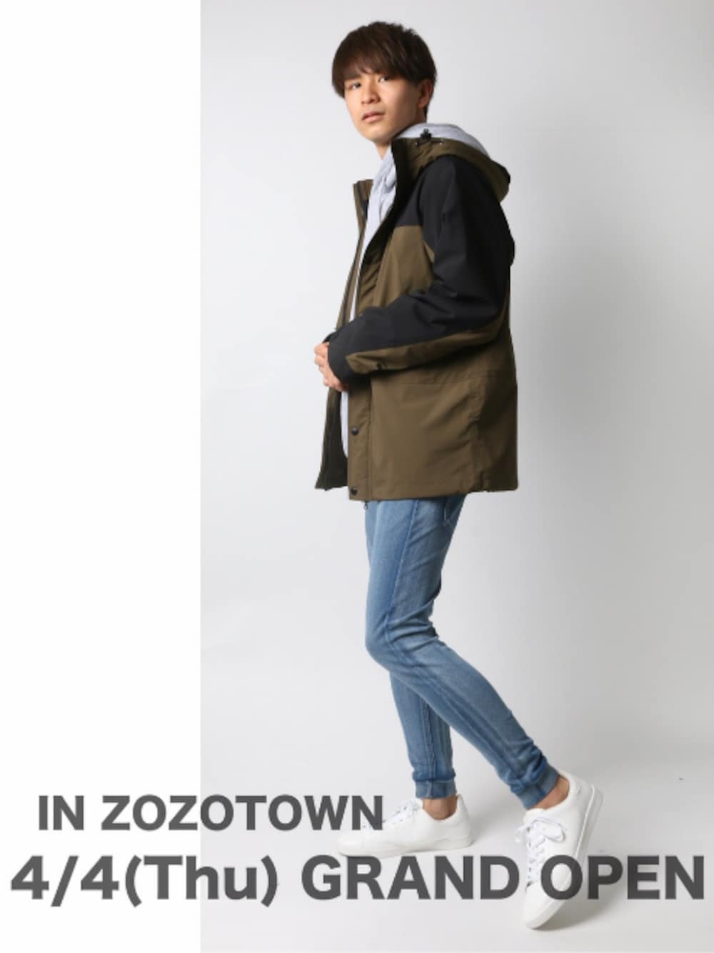 グリーン系のマウンテンパーカー、グレー系のパーカー、ブルー系のスウェットパンツを着用したメンズの春コーディネートの1枚目の写真