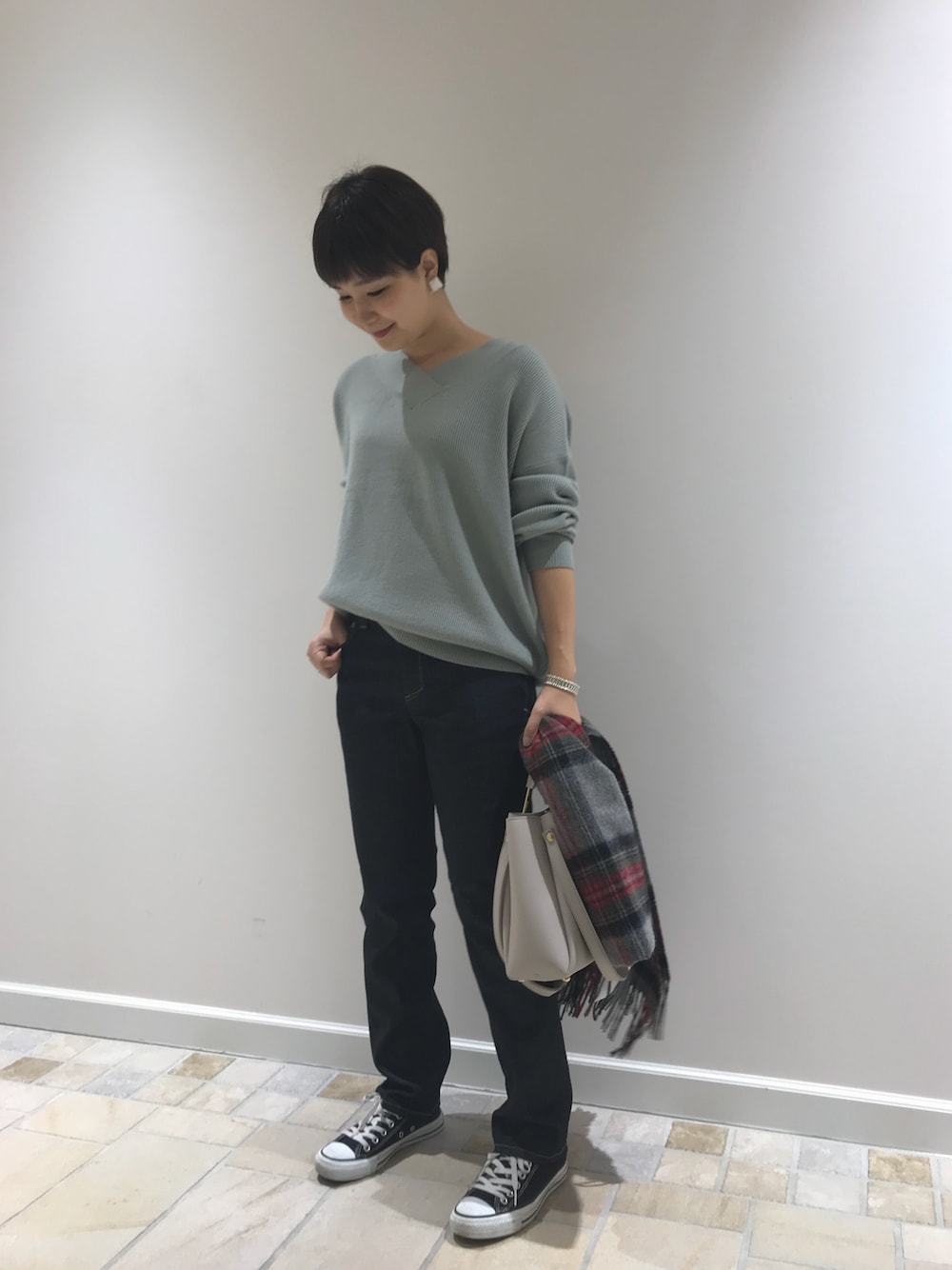 グリーン系のニット/セーター、ブルー系のデニムパンツ、グレー系のショルダーバッグを着用したレディースの秋コーディネートの1枚目の写真