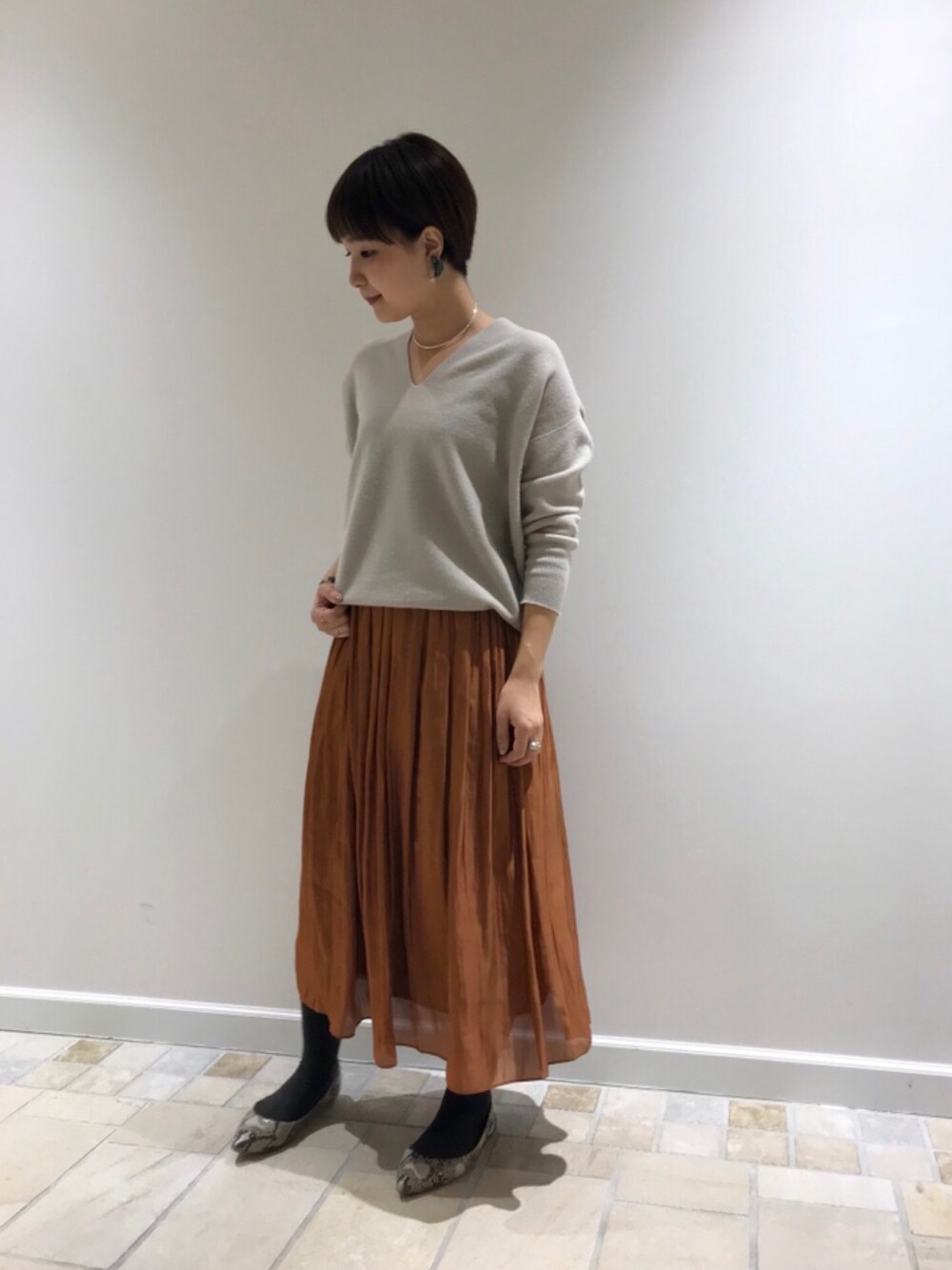 ピンク系のニット/セーター、レッド系のスカート、シルバー系のネックレスを着用したレディースの秋コーディネートの1枚目の写真