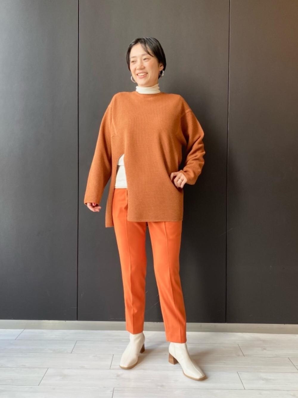 ホワイト系のTシャツ/カットソー、ホワイト系のブーツ、オレンジ系のニット/セーターを着用したレディースの秋コーディネートの1枚目の写真