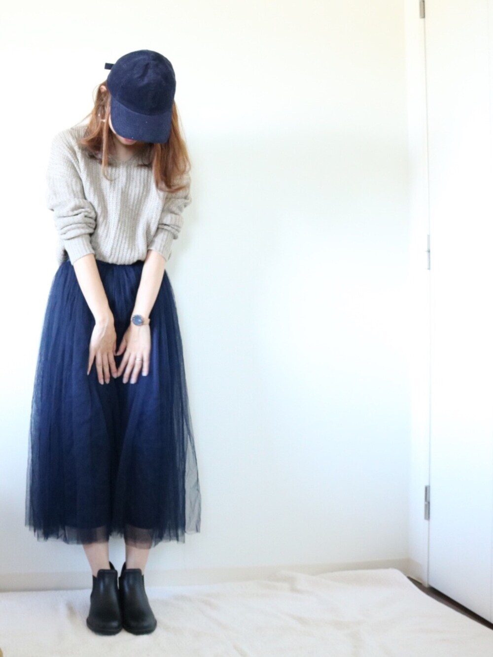 ベージュ系のニット/セーター、ブルー系のスカート、ブラック系のアナログ腕時計を着用したレディースの秋コーディネートの1枚目の写真