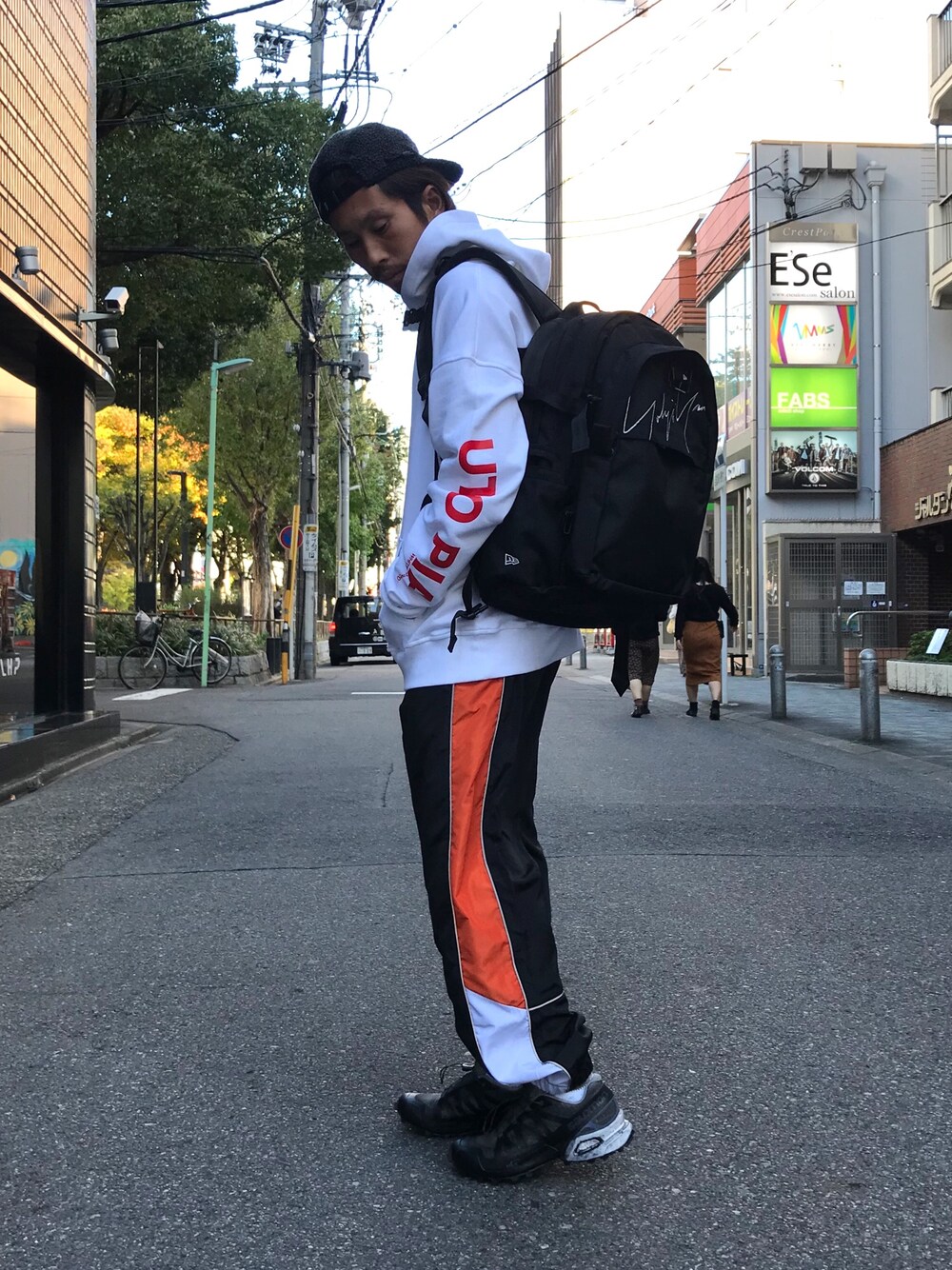 ホワイト系のパーカー、ブラック系のスニーカー、ブラック系のバックパック/リュックを着用したメンズの秋コーディネートの1枚目の写真
