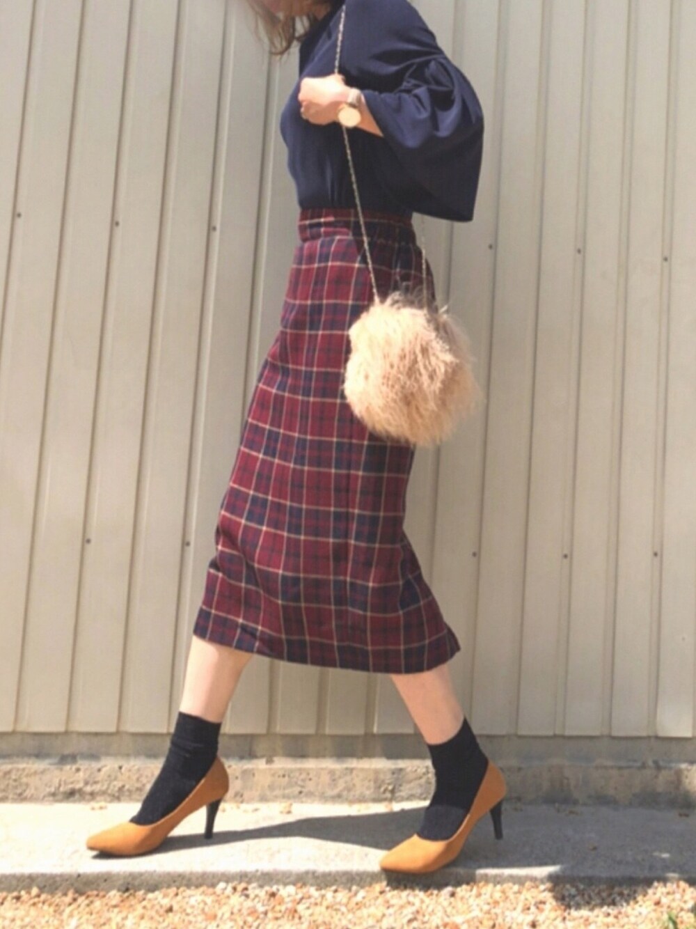 レッド系のスカート、ベージュ系のショルダーバッグ、イエロー系のパンプスを着用したレディースの秋コーディネートの1枚目の写真