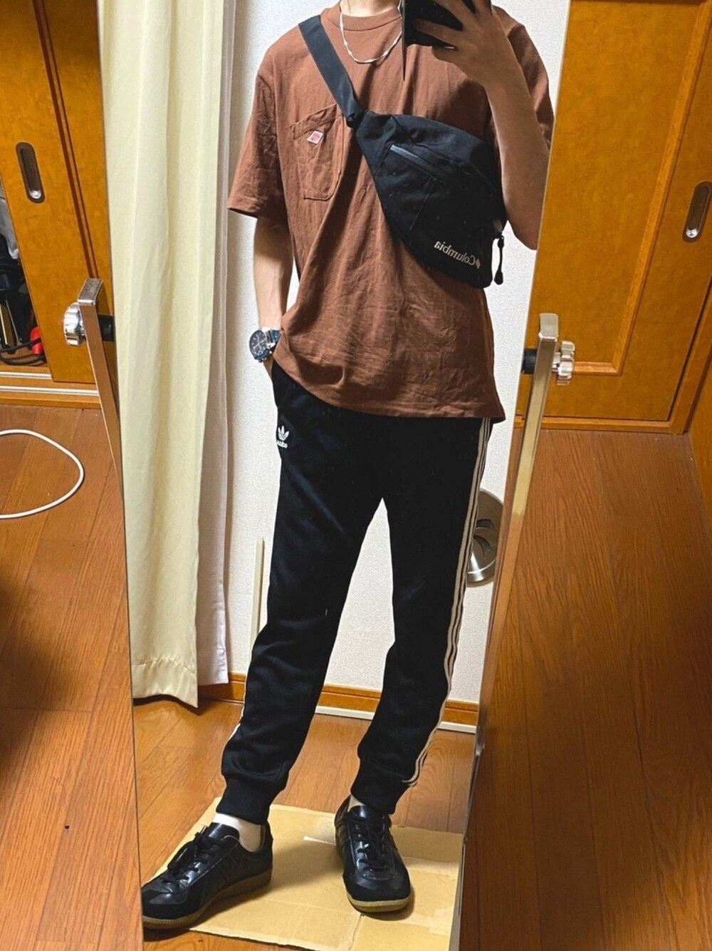 ブラック系のショルダーバッグ、レッド系のTシャツ/カットソー、ブラック系のスウェットパンツを着用したメンズの夏コーディネートの1枚目の写真