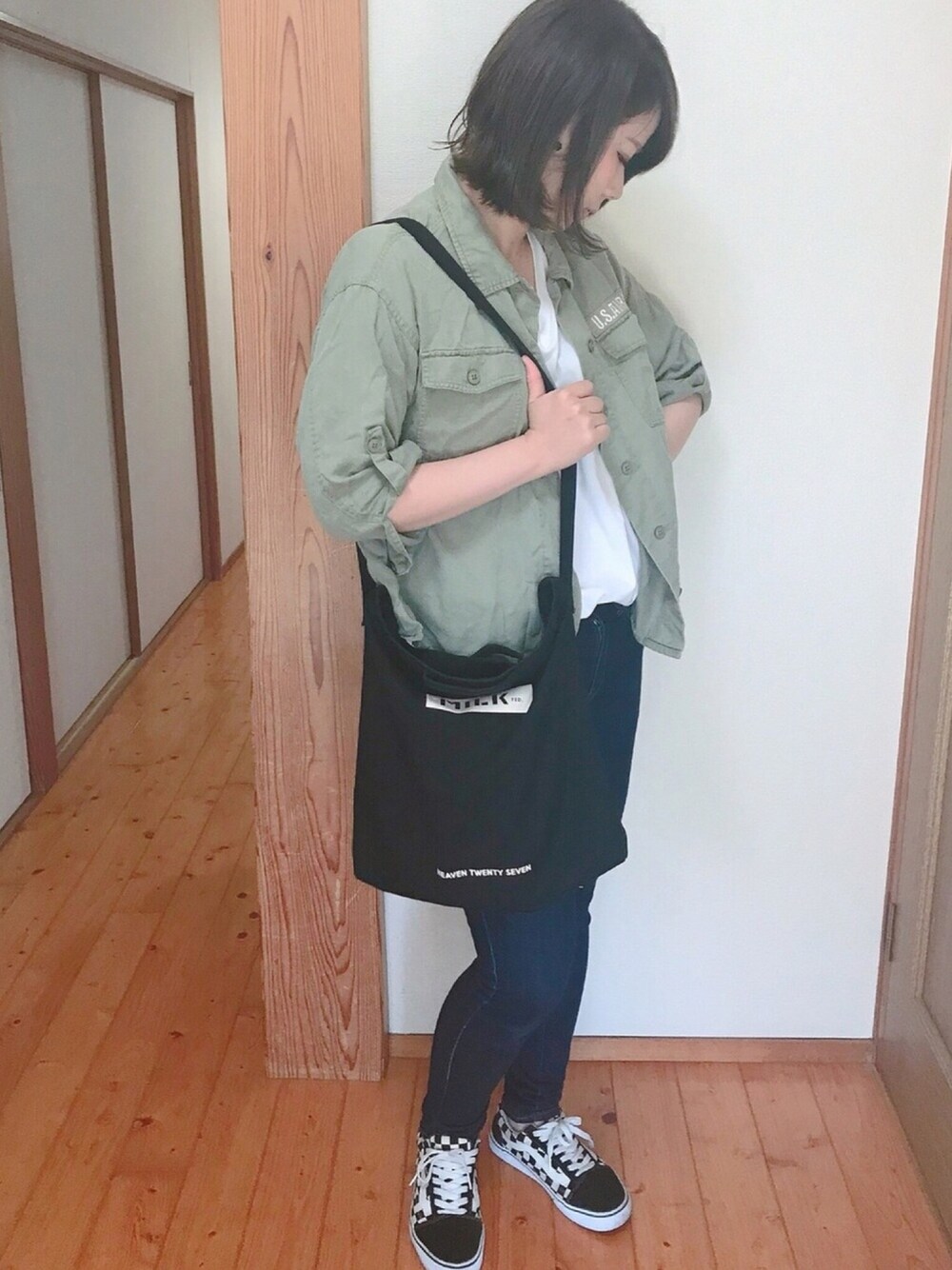 ブラック系のトートバッグ、グリーン系のミリタリージャケット、ブルー系のデニムパンツを着用したレディースの春コーディネートの1枚目の写真