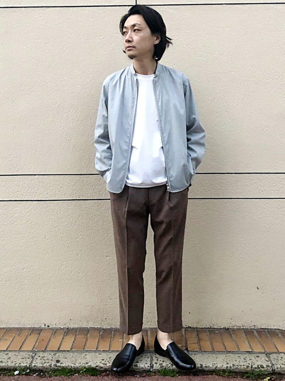 ブラック系のスリッポン、グレー系のブルゾン、ベージュ系のスラックスを着用したメンズの春コーディネートの1枚目の写真