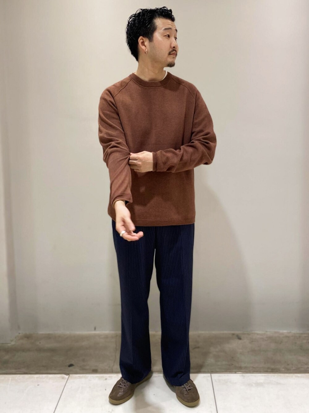 レッド系のニット/セーター、ブルー系のチノパンツ、グレー系のスニーカーを着用したメンズの秋コーディネートの1枚目の写真