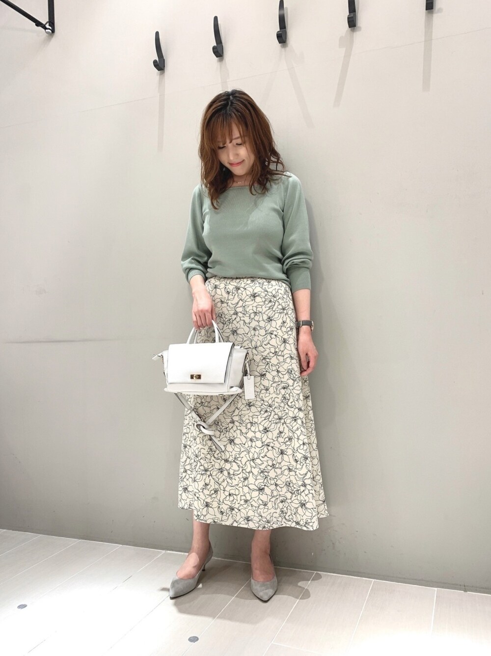 グリーン系のニット/セーター、ホワイト系のスカート、ホワイト系のバッグを着用したレディースの春コーディネートの1枚目の写真