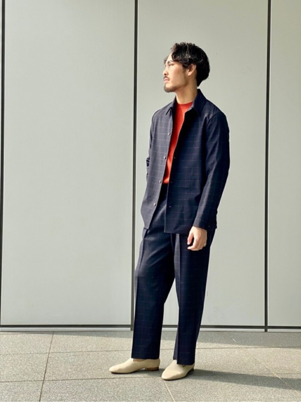 オレンジ系のニット/セーター、グレー系のシャツ/ブラウス、グレー系のその他パンツを着用したメンズの春コーディネートの1枚目の写真