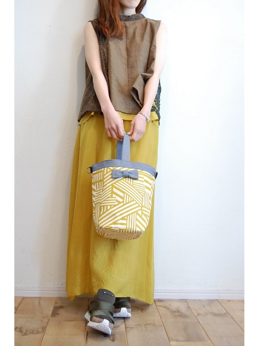 イエロー系のハンドバッグ、グリーン系のスニーカー、グリーン系のシャツ/ブラウスを着用したレディースの春コーディネートの1枚目の写真