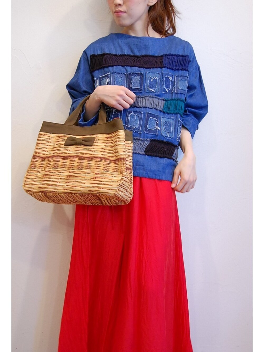 レッド系のワンピース、ブラウン系のトートバッグ、ブルー系のシャツ/ブラウスを着用したレディースの春コーディネートの1枚目の写真