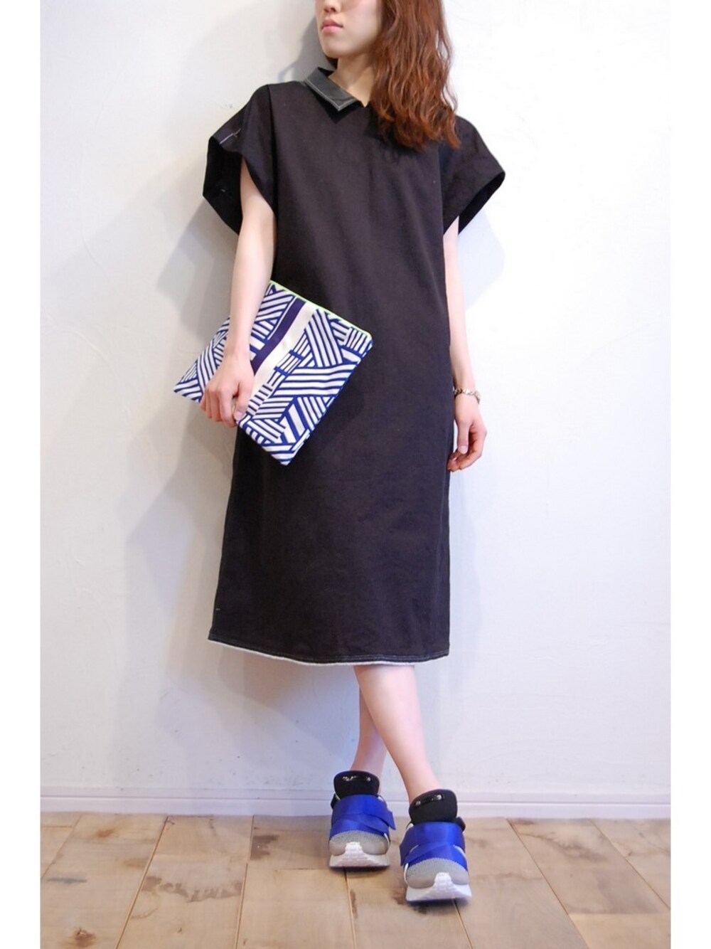 ブラック系のワンピース、ブルー系のスニーカー、ブルー系のクラッチバッグを着用したレディースの春コーディネートの1枚目の写真