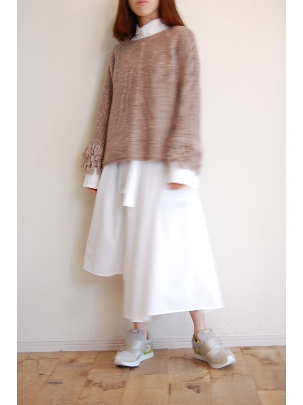 ベージュ系のニット/セーター、ホワイト系のシャツワンピース、グレー系のスニーカーを着用したレディースの秋コーディネートの1枚目の写真
