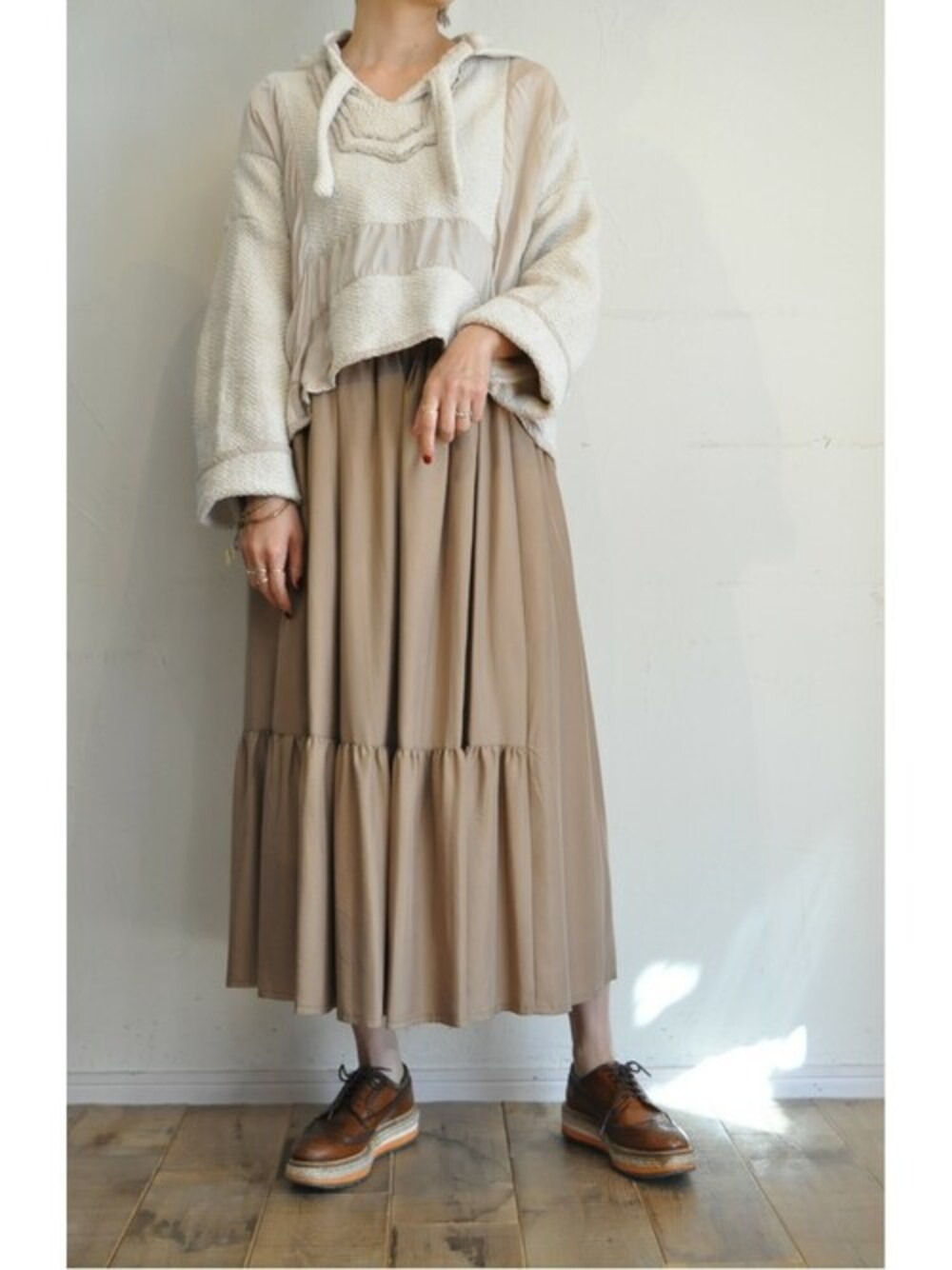 ベージュ系のスカート、ホワイト系のパーカーを着用したレディースの秋コーディネートの1枚目の写真
