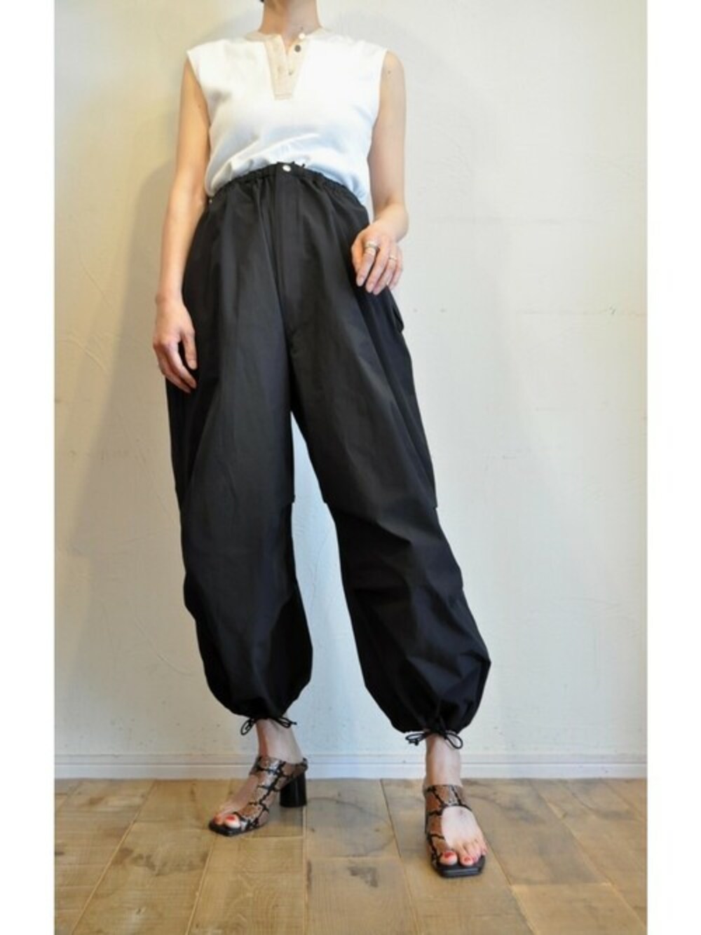 ホワイト系のタンクトップ、ブラック系のカーゴパンツを着用したレディースの夏コーディネートの1枚目の写真