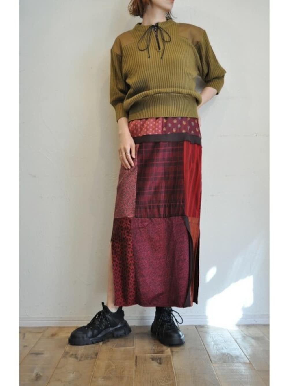 レッド系のワンピース、ブラウン系のニット/セーターを着用したレディースの秋コーディネートの1枚目の写真