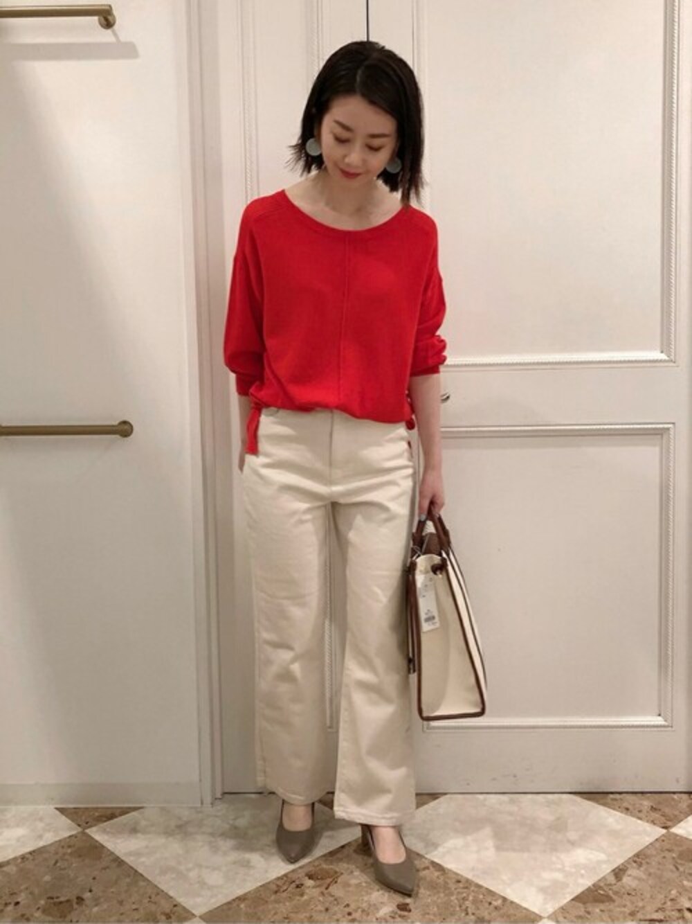 ベージュ系のデニムパンツ、レッド系のニット/セーターを着用したレディースの春コーディネートの1枚目の写真