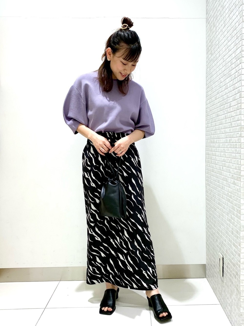 パープル系のニット/セーター、ブラック系のショルダーバッグ、ブラック系のスカートを着用したレディースの春コーディネートの1枚目の写真