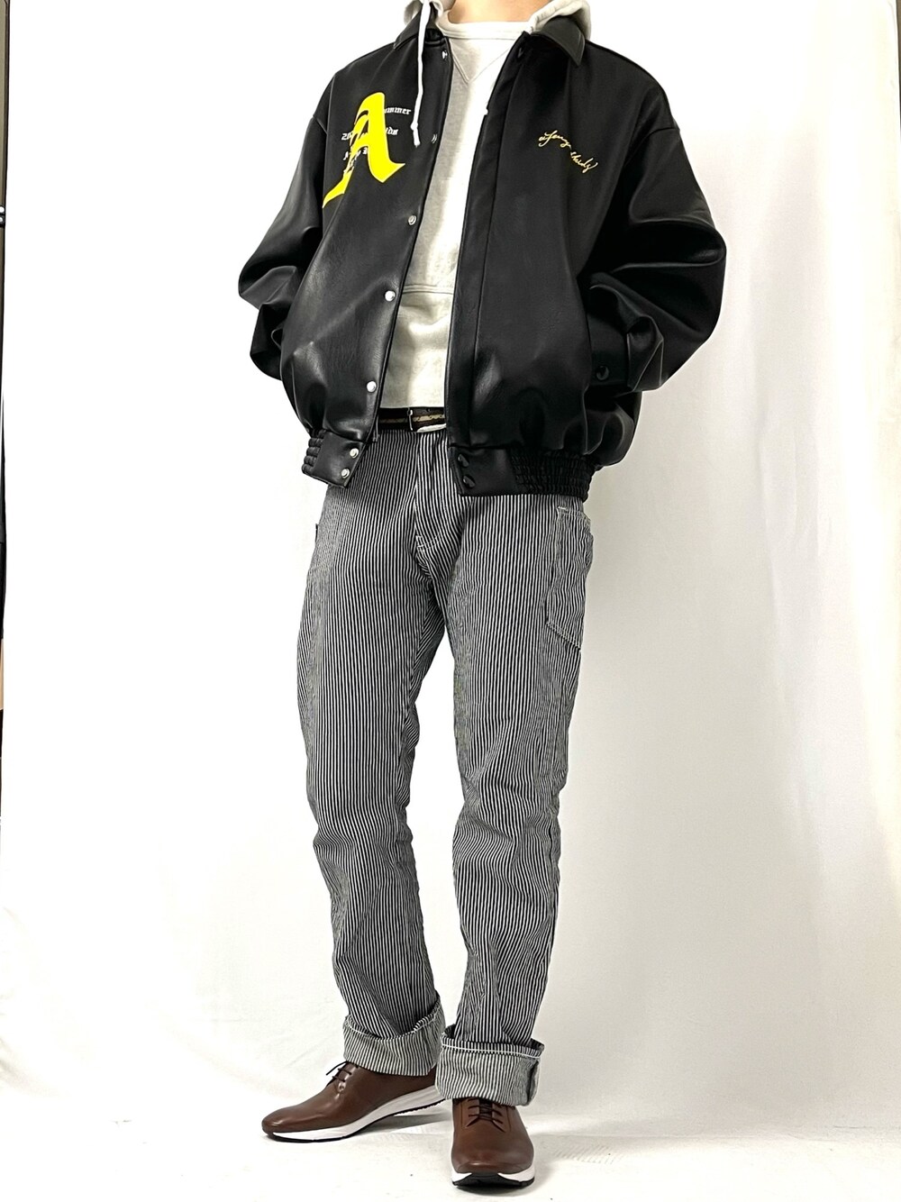 ブラック系のジャケット/アウター、ベージュ系のパーカー、ブルー系のデニムパンツを着用したメンズの冬コーディネートの1枚目の写真