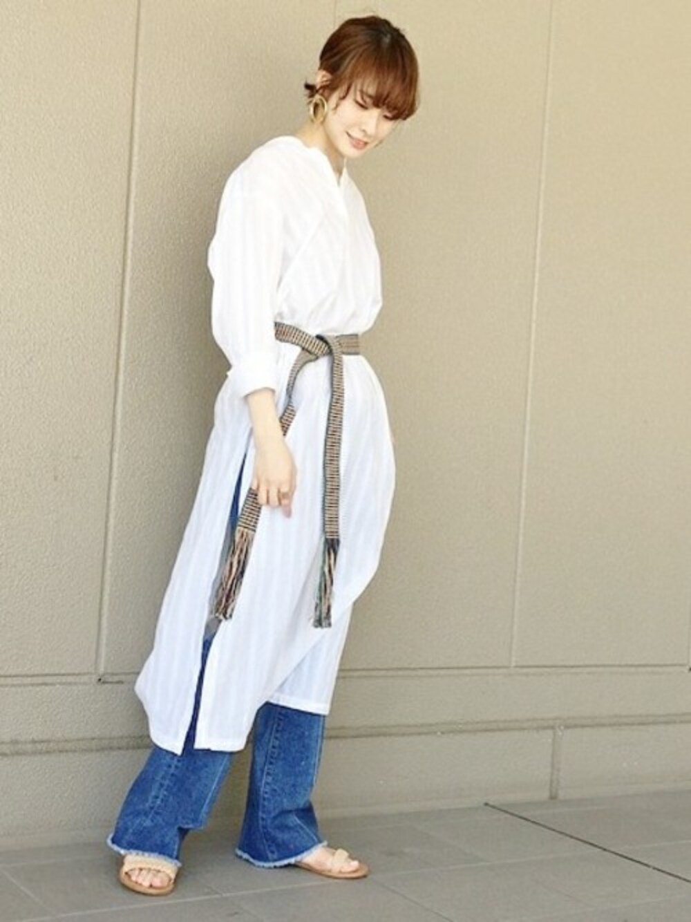 ブルー系のデニムパンツ、ホワイト系のシャツワンピース、ベージュ系のサンダルを着用したレディースの夏コーディネートの1枚目の写真