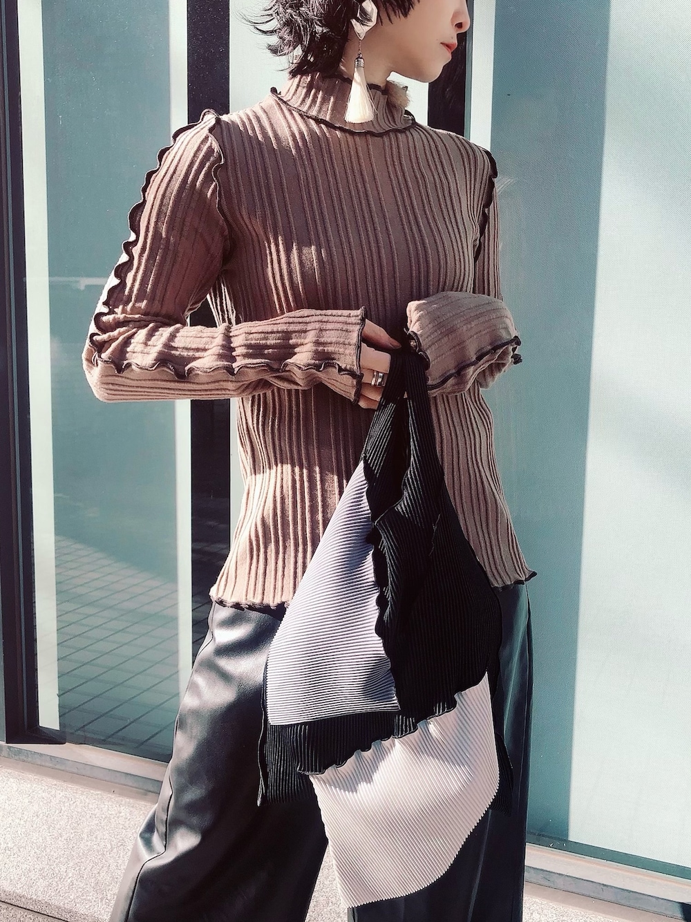 ベージュ系のニット/セーター、ブラック系のエコバッグ/サブバッグ、ホワイト系のイヤリングを着用したレディースの冬コーディネートの1枚目の写真