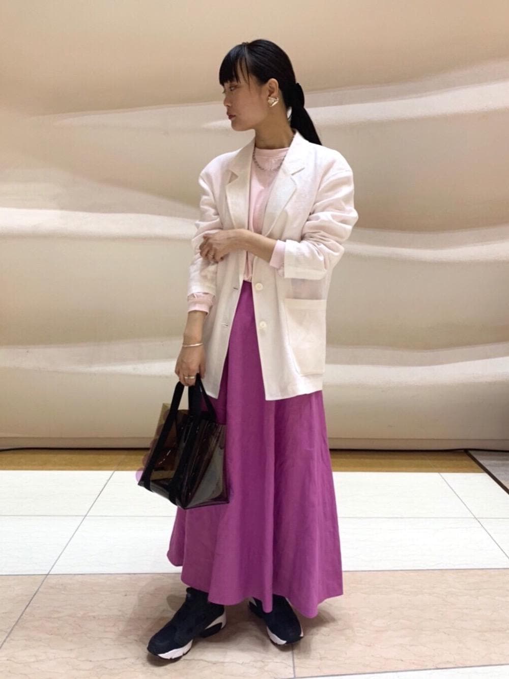 ホワイト系のテーラードジャケット、ピンク系のスカート、ブラウン系のトートバッグを着用したレディースの春コーディネートの1枚目の写真