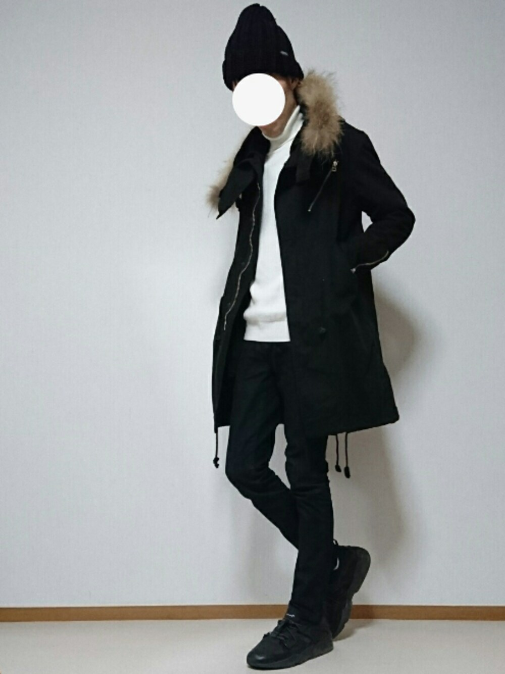 ブラック系のモッズコート、ホワイト系のニット/セーター、ブルー系のデニムパンツを着用したメンズの冬コーディネートの1枚目の写真