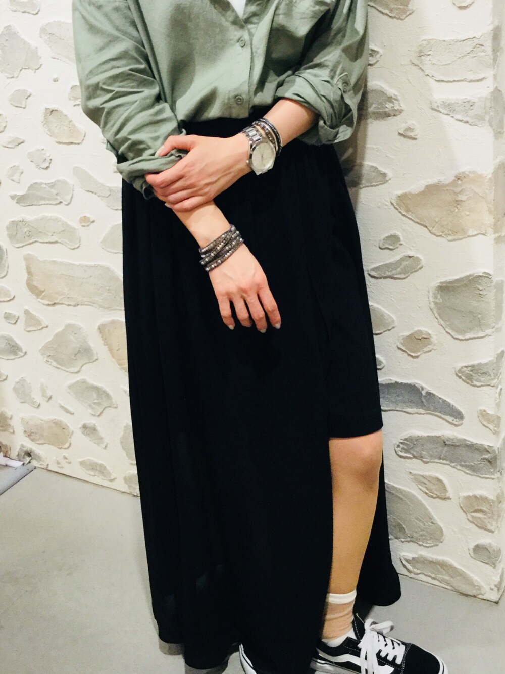 ブラック系のスニーカー、ブラック系のスカート、グリーン系のシャツ/ブラウスを着用したレディースの春コーディネートの1枚目の写真