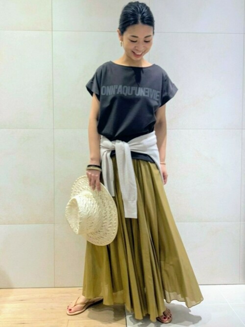 グレー系のTシャツ/カットソー、ベージュ系のスカート、ホワイト系のニット/セーターを着用したレディースの夏コーディネートの1枚目の写真