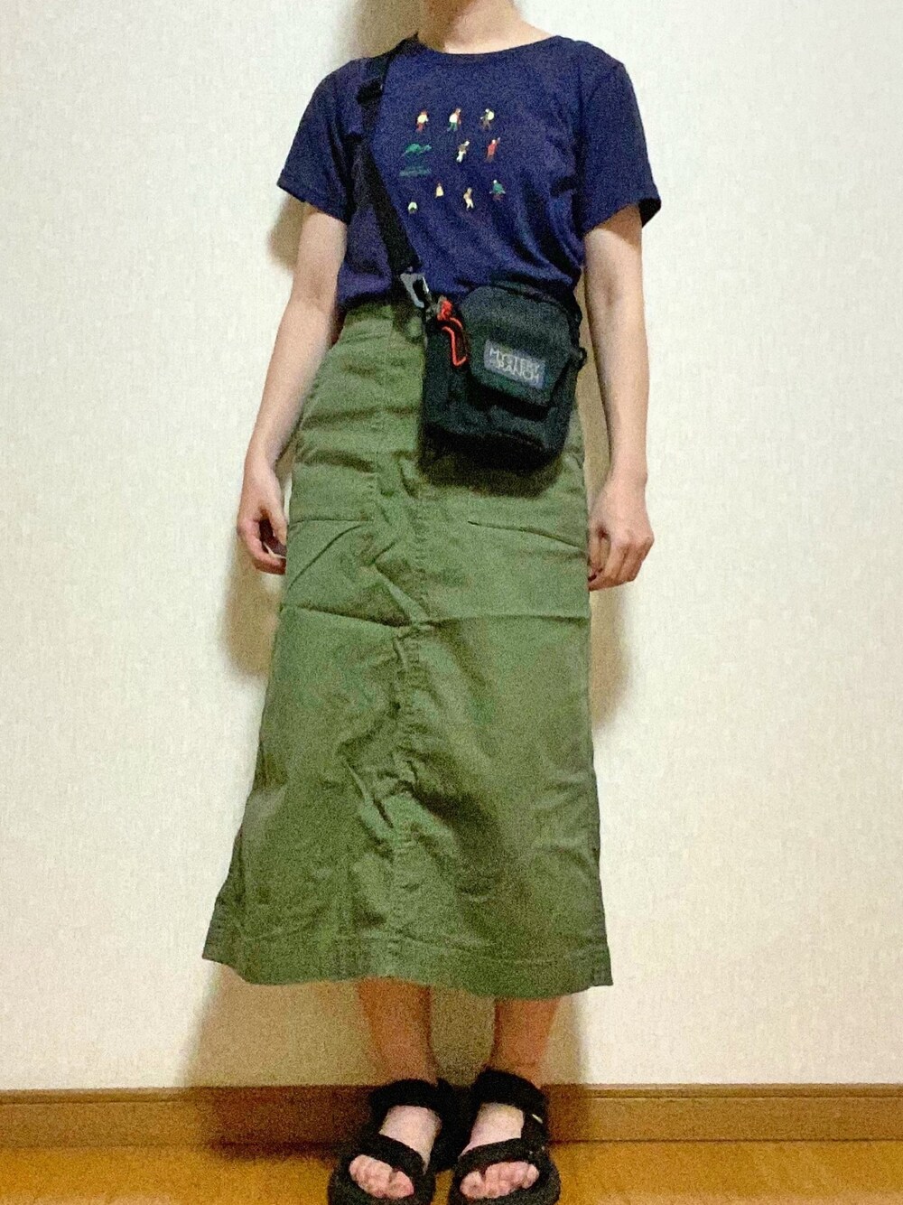 グリーン系のスカート、パープル系のTシャツ/カットソー、ブラック系のショルダーバッグを着用したレディースの春コーディネートの1枚目の写真