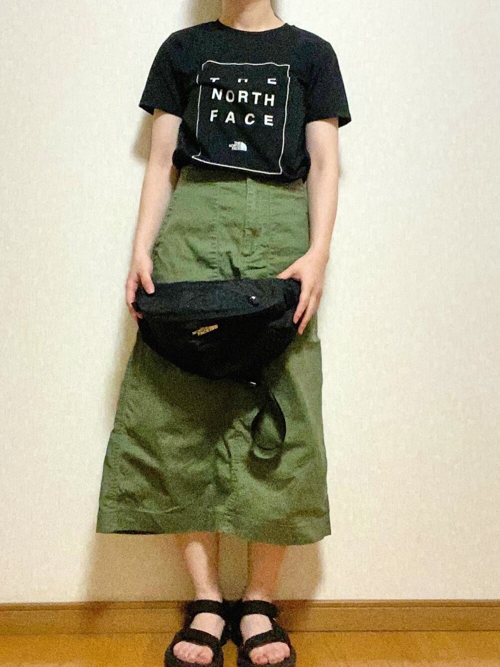 ブラック系のTシャツ/カットソー、ブラック系のショルダーバッグ、グリーン系のスカートを着用したレディースの春コーディネートの1枚目の写真