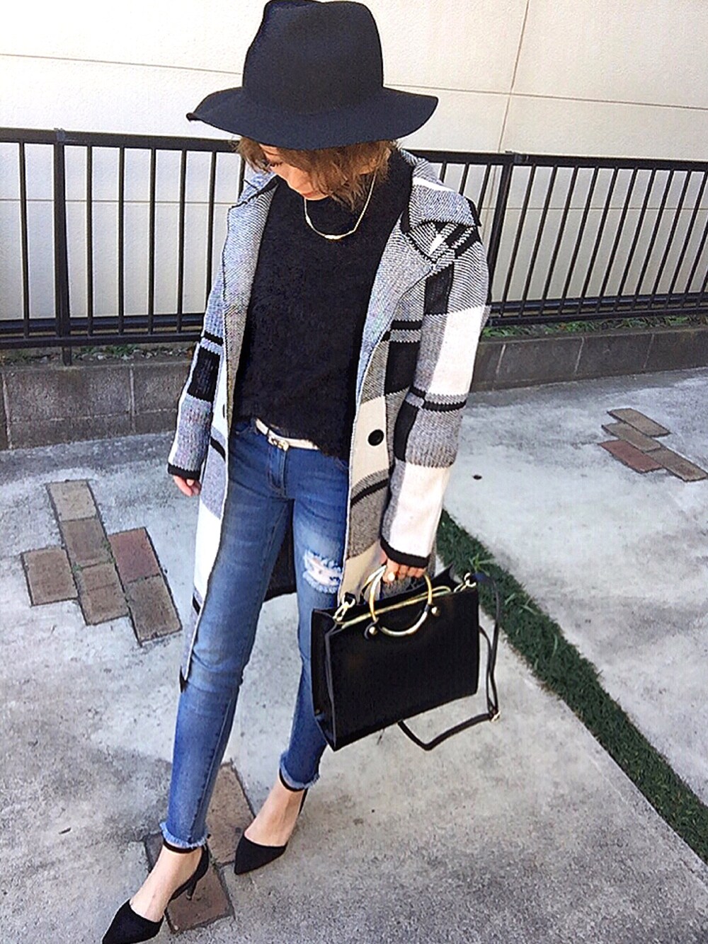 ブラック系のニット/セーター、ブルー系のデニムパンツ、ブラック系のパンプスを着用したレディースの冬コーディネートの1枚目の写真
