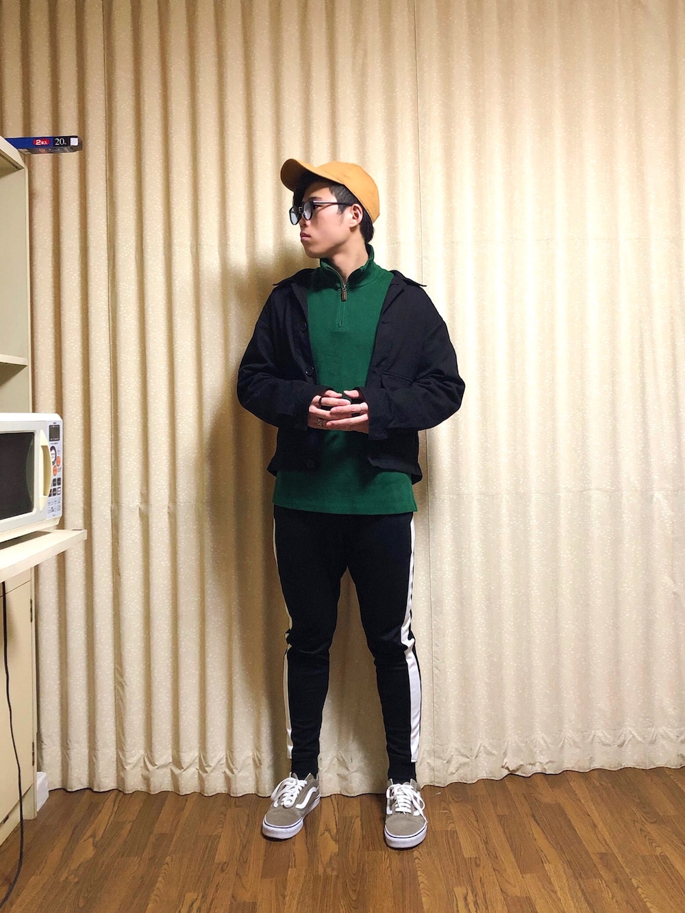 ブラック系のカバーオール、グリーン系のトップス、ブラック系のスウェットパンツを着用したメンズの秋コーディネートの1枚目の写真