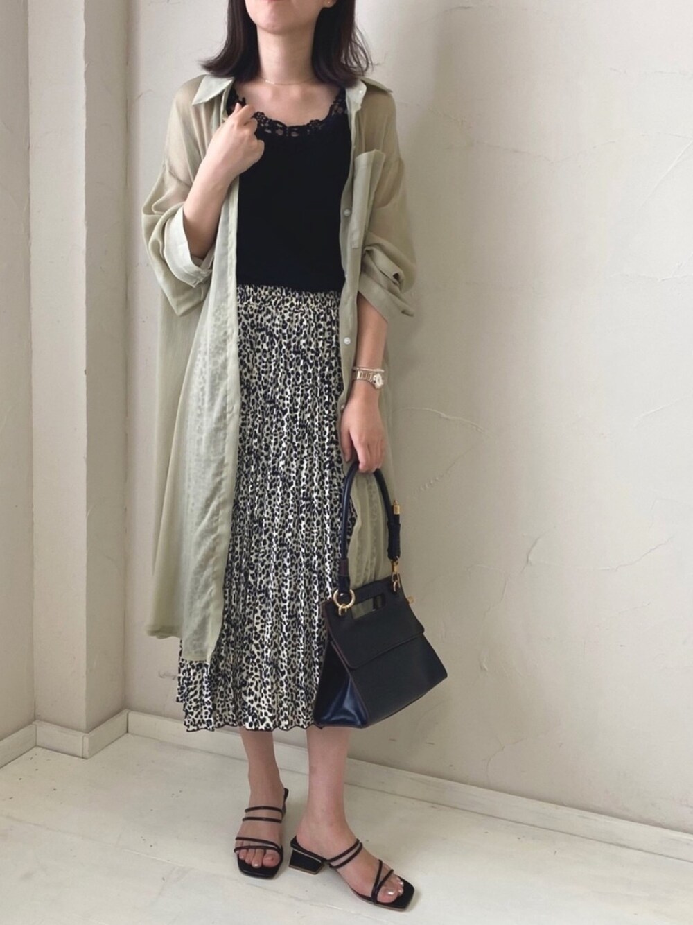 グリーン系のシャツワンピース、ホワイト系のスカート、ブラック系のタンクトップを着用したレディースの夏コーディネートの1枚目の写真