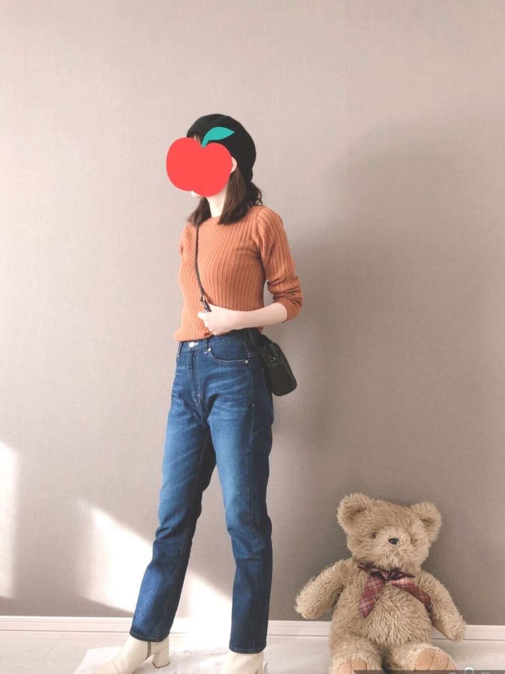 ブラック系のショルダーバッグ、ブルー系のデニムパンツ、オレンジ系のニット/セーターを着用したレディースの冬コーディネートの1枚目の写真
