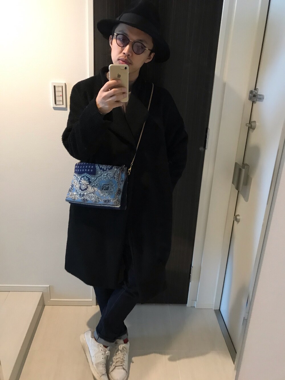 ブラック系のノーカラージャケット、ブルー系のバッグ、ブルー系のデニムパンツを着用したメンズの冬コーディネートの1枚目の写真