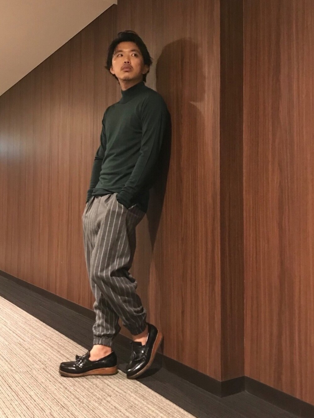 グリーン系のニット/セーター、グレー系のその他パンツ、ブラック系のシューズを着用したメンズの秋コーディネートの1枚目の写真