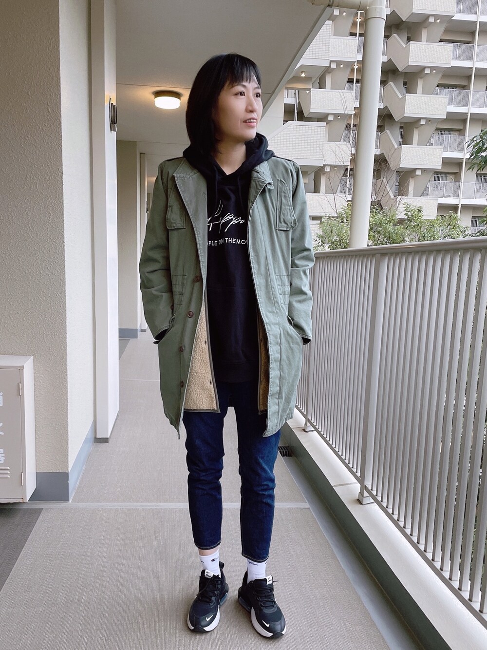 グリーン系のミリタリージャケット、ブラック系のパーカーを着用したレディースの冬コーディネートの1枚目の写真