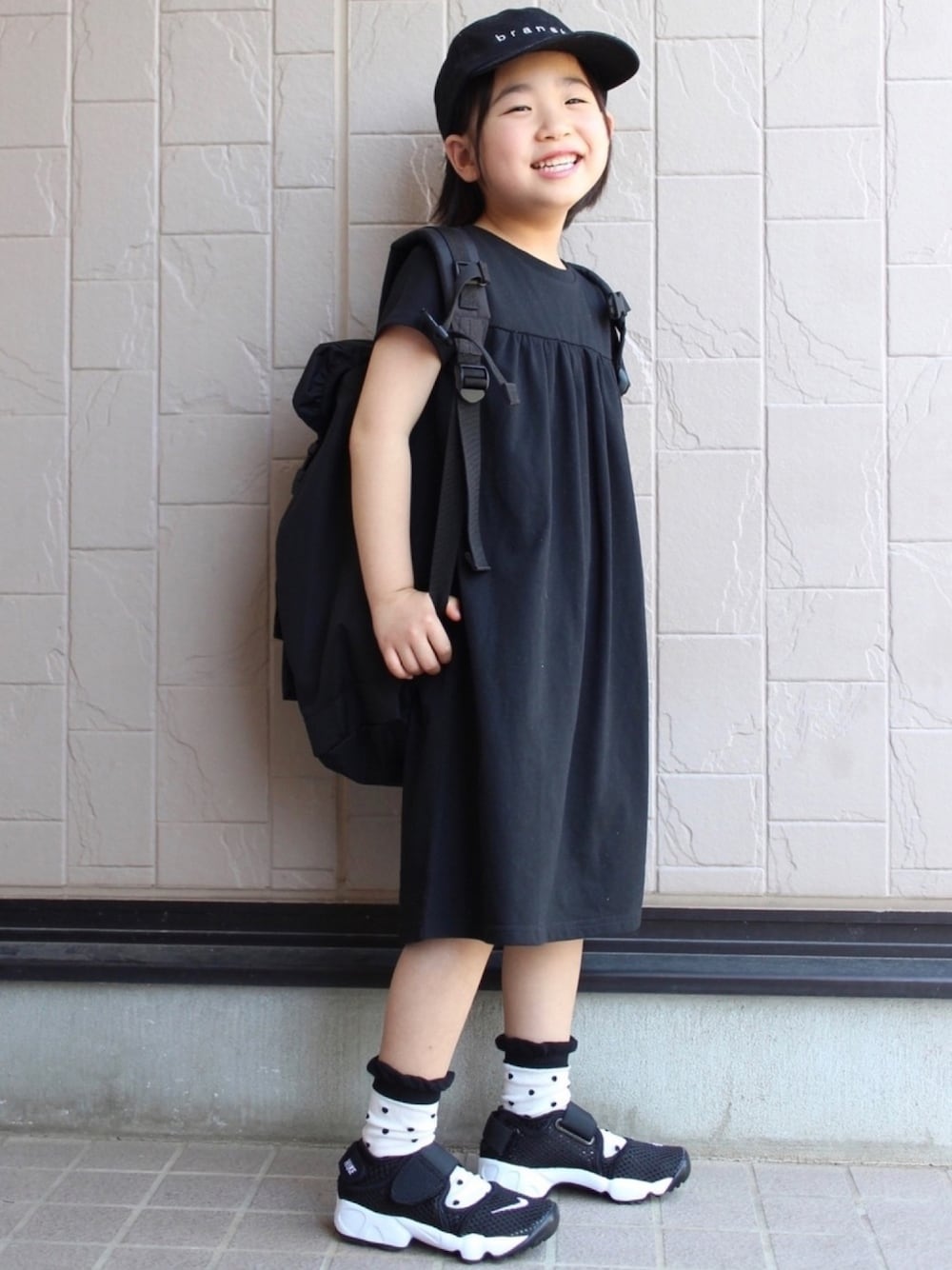 ブラック系のワンピース、ブラック系のスニーカー、ブラック系のソックス/靴下を着用したキッズの春コーディネートの1枚目の写真