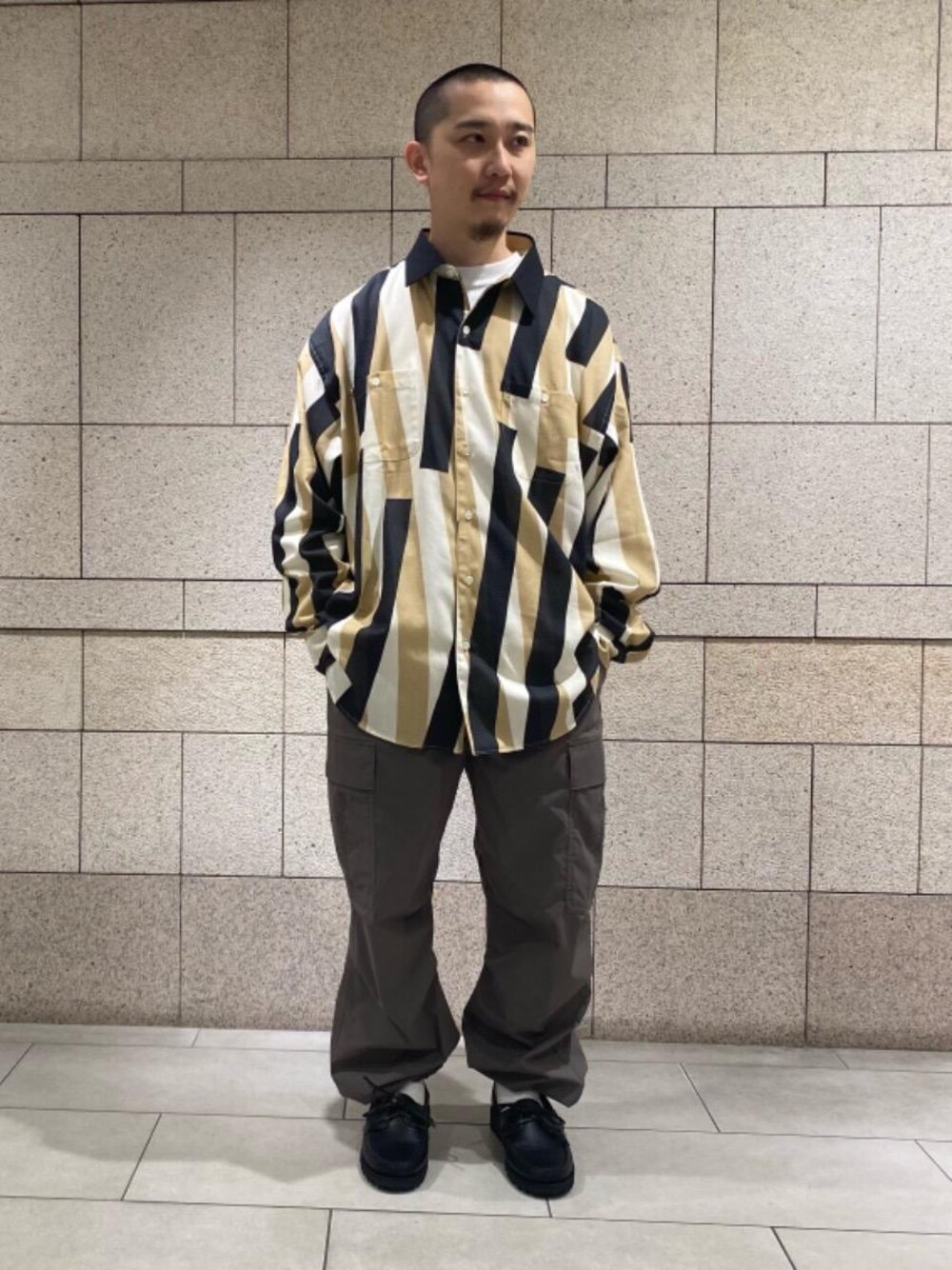 ブラック系のモカシン/デッキシューズ、グリーン系のカーゴパンツ、ベージュ系のシャツ/ブラウスを着用したメンズの春コーディネートの1枚目の写真