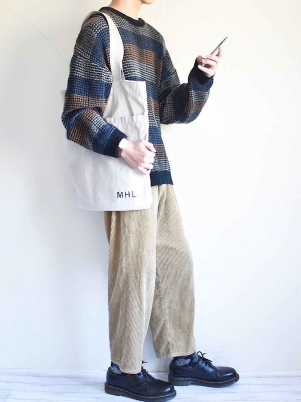ブルー系のニット/セーター、イエロー系のその他パンツ、ブラック系のブーツを着用したメンズの秋コーディネートの1枚目の写真