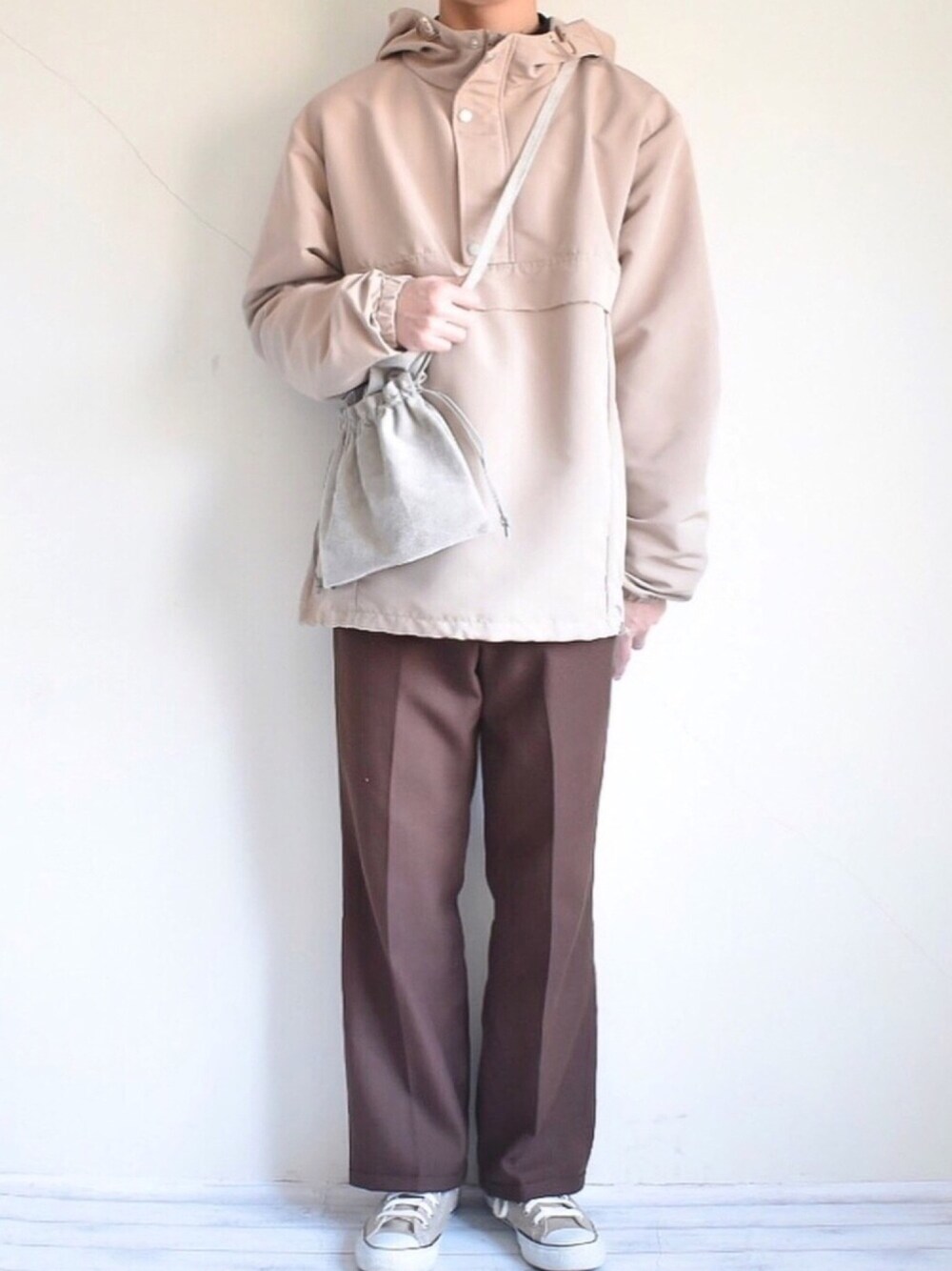 ベージュ系のマウンテンパーカー、ブラウン系のパンツ、グレー系のショルダーバッグを着用したメンズの春コーディネートの1枚目の写真