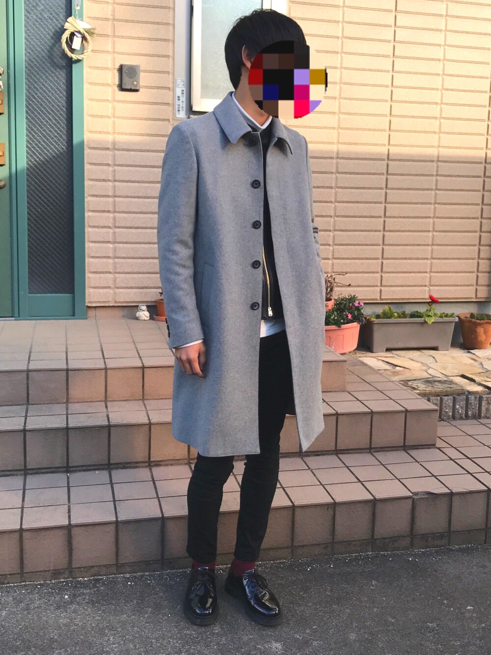 グレー系のステンカラーコート、ブラック系のライダースジャケット、ホワイト系のTシャツ/カットソーを着用したメンズの冬コーディネートの1枚目の写真