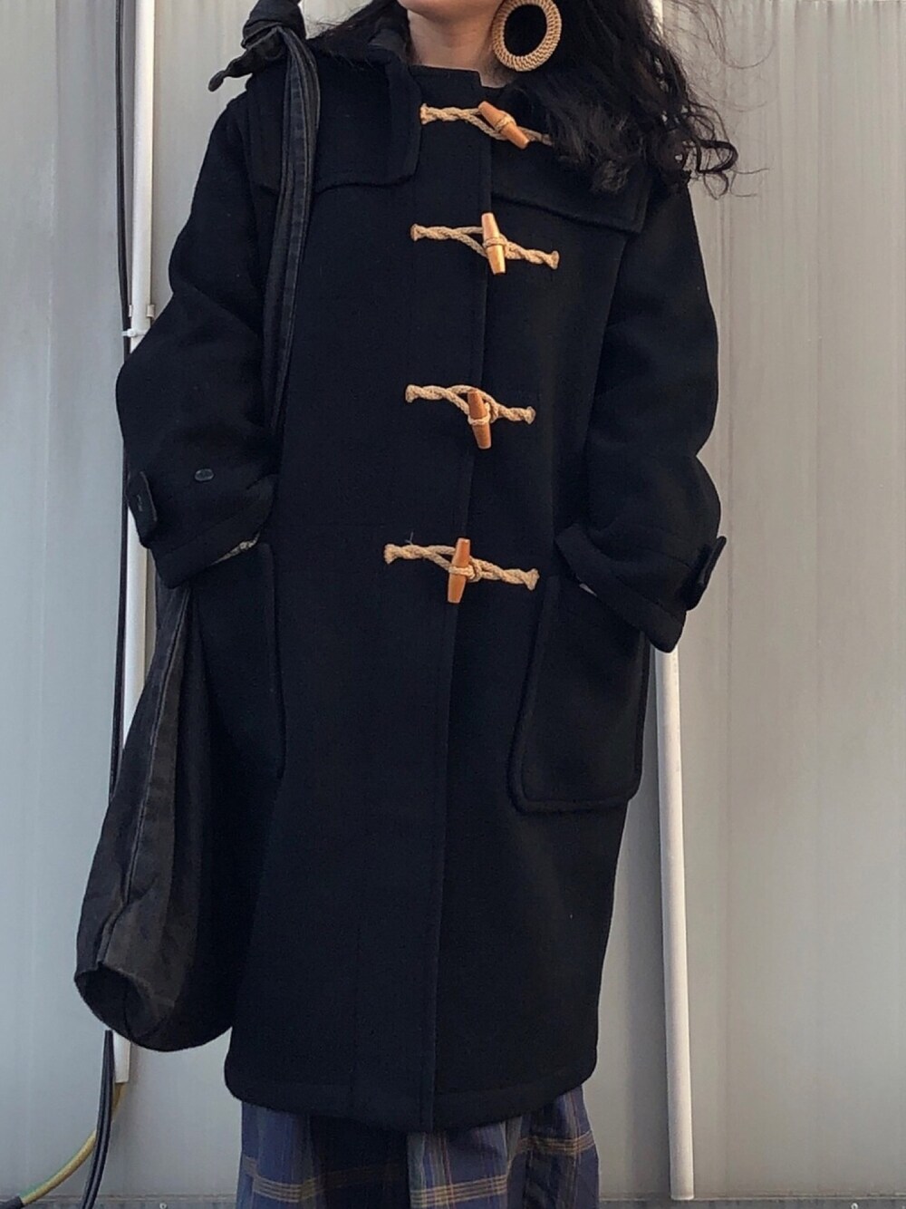 ブラック系のダッフルコート、ブラック系のショルダーバッグ、ベージュ系のイヤリングを着用したレディースの春コーディネートの1枚目の写真